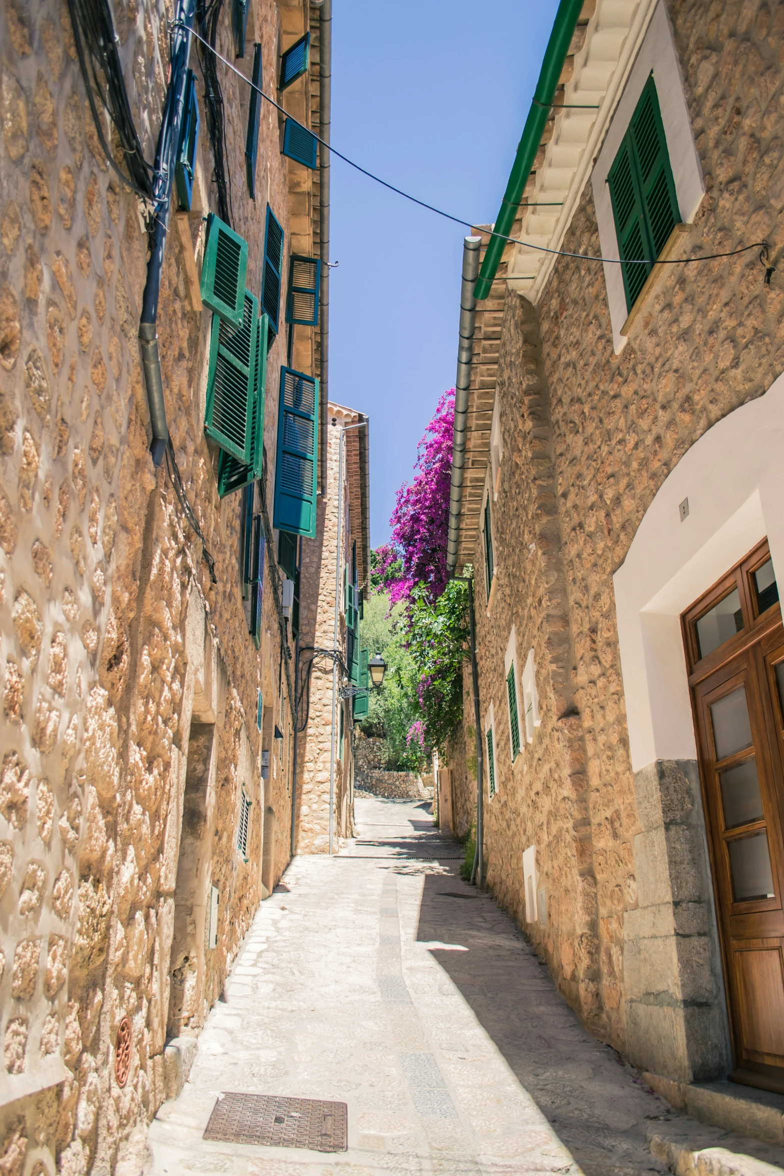 a narrow street with green shutters and brick buildings