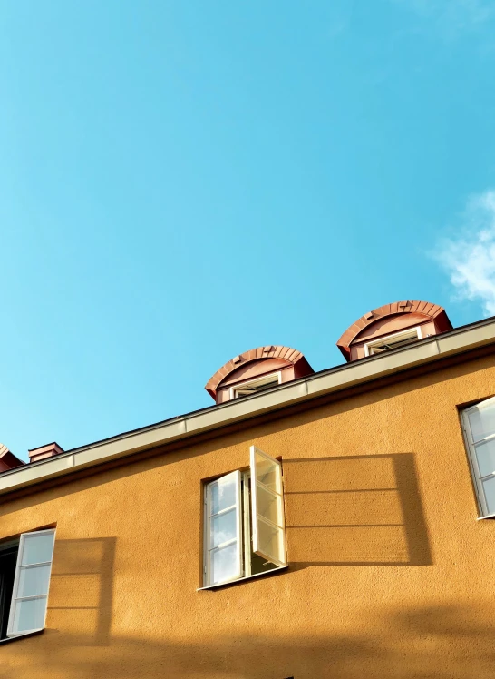 three windows are opened on a yellow building