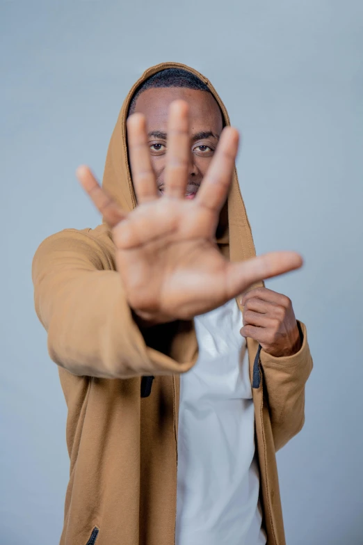 a man wearing a hoodie making an open hand gesture