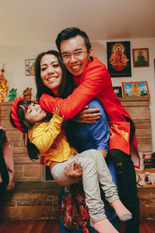 a man and woman in red are smiling with a child