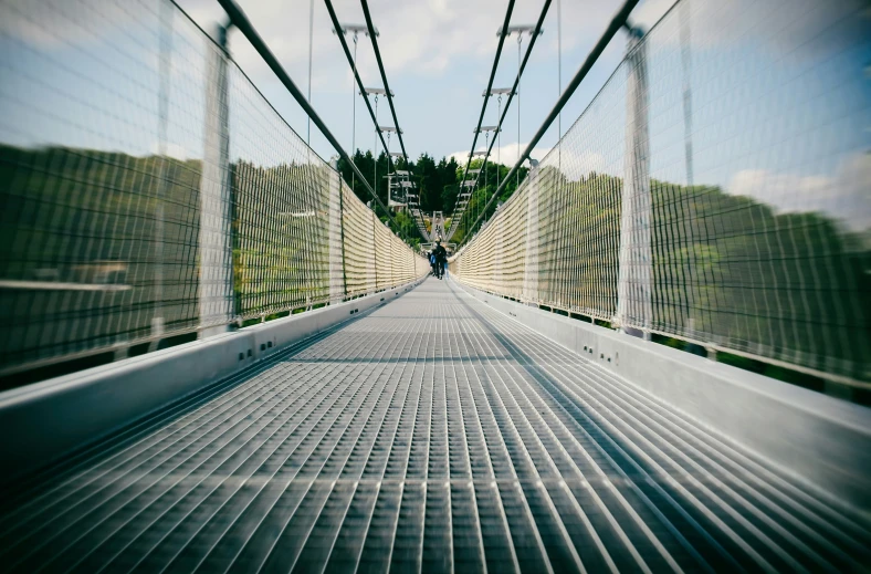 people crossing over a bridge with a net and wires