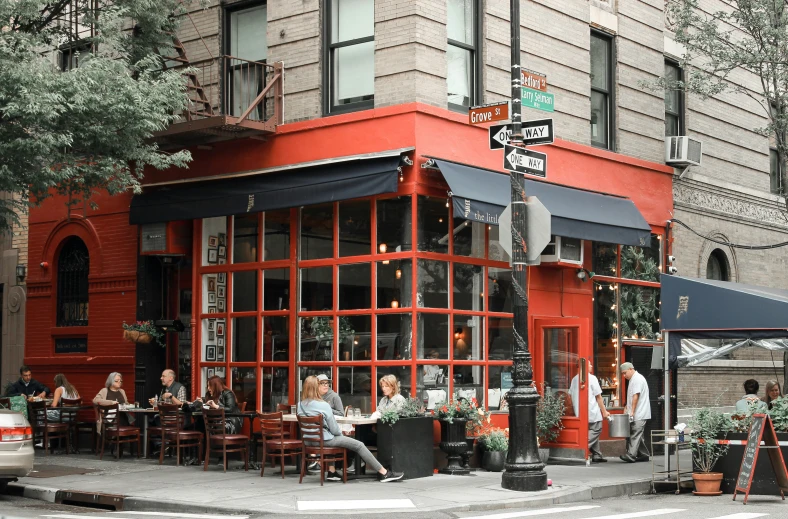 a group of people outside a building at an outdoor dining table