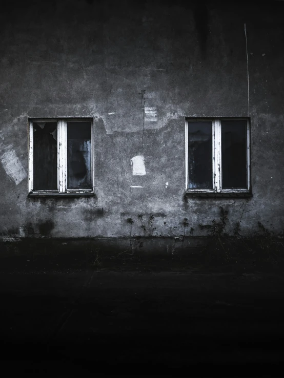 an old gray building with windows and broken blinds