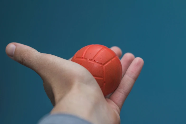 a hand that is holding a red ball