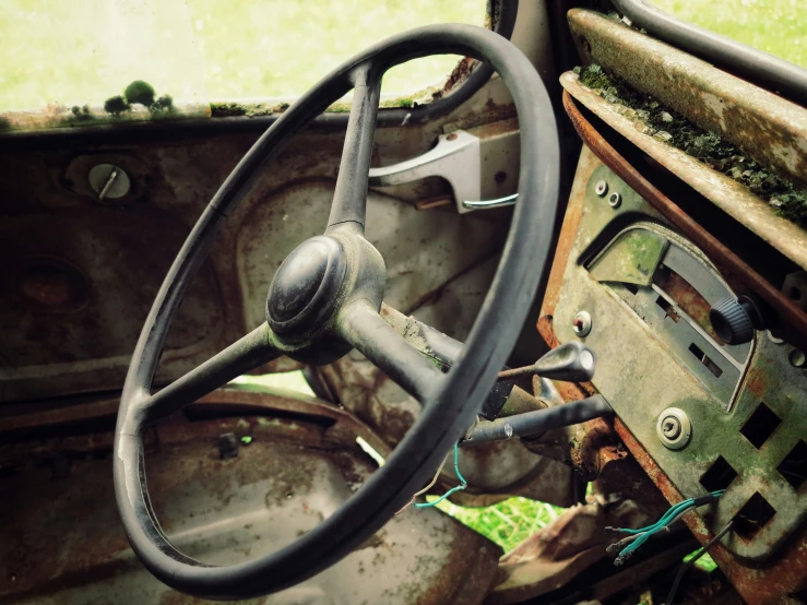 the dashboard of an old, run down car in an abandoned field