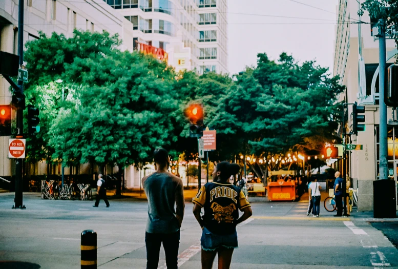 the two people stand looking at the traffic lights