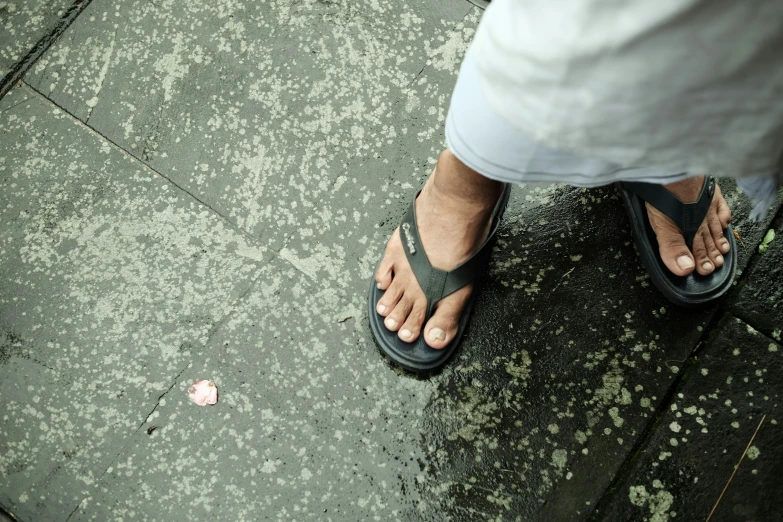 a persons feet with their sandals open on the sidewalk