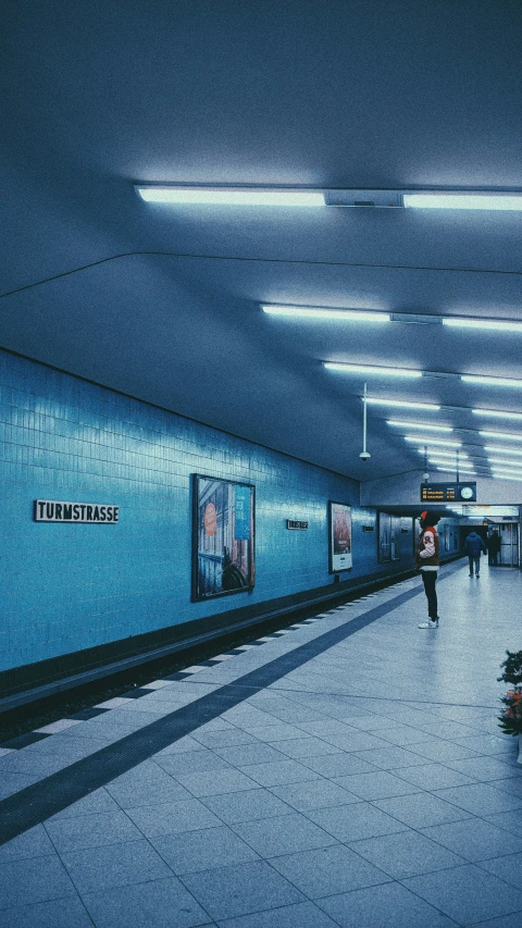 the corridor with the blue walls has people walking along