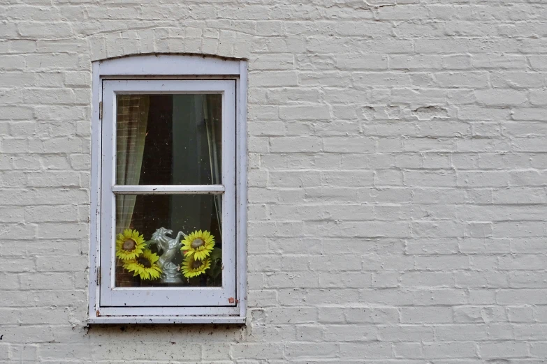 a white brick wall with a window and flower display