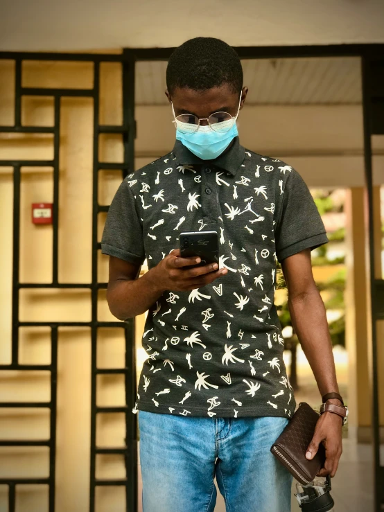 a man with protective mask and black shirt looks at a cell phone