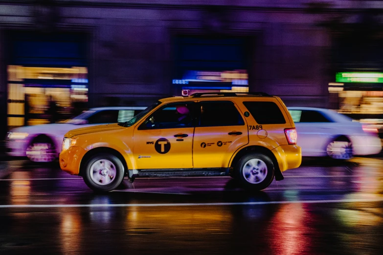 a yellow taxi is going down the street in the rain