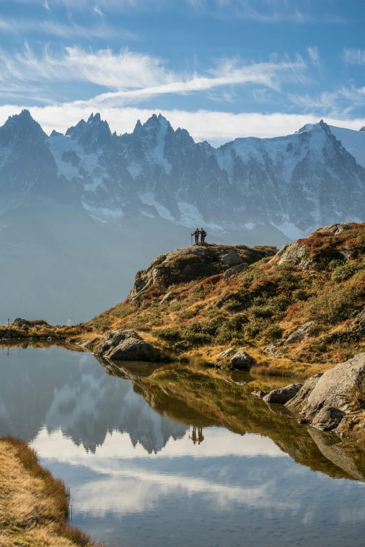 a mountain range sits near the water, with mountains behind it