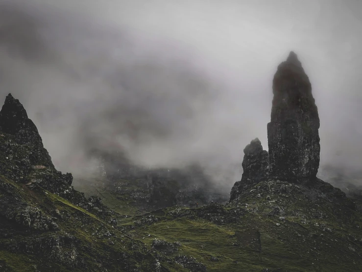 dark colored mountains with clouds above them and trees in the foreground