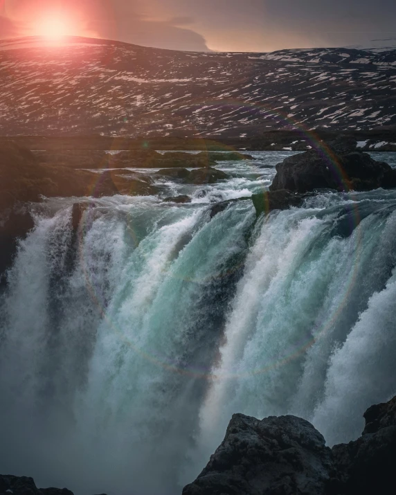 the sun setting over a big waterfall with many rapids