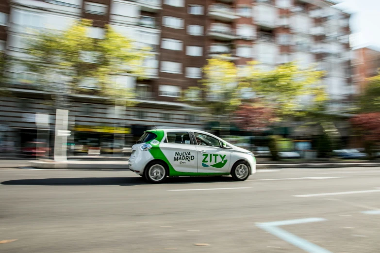 a small green car is driving down the street