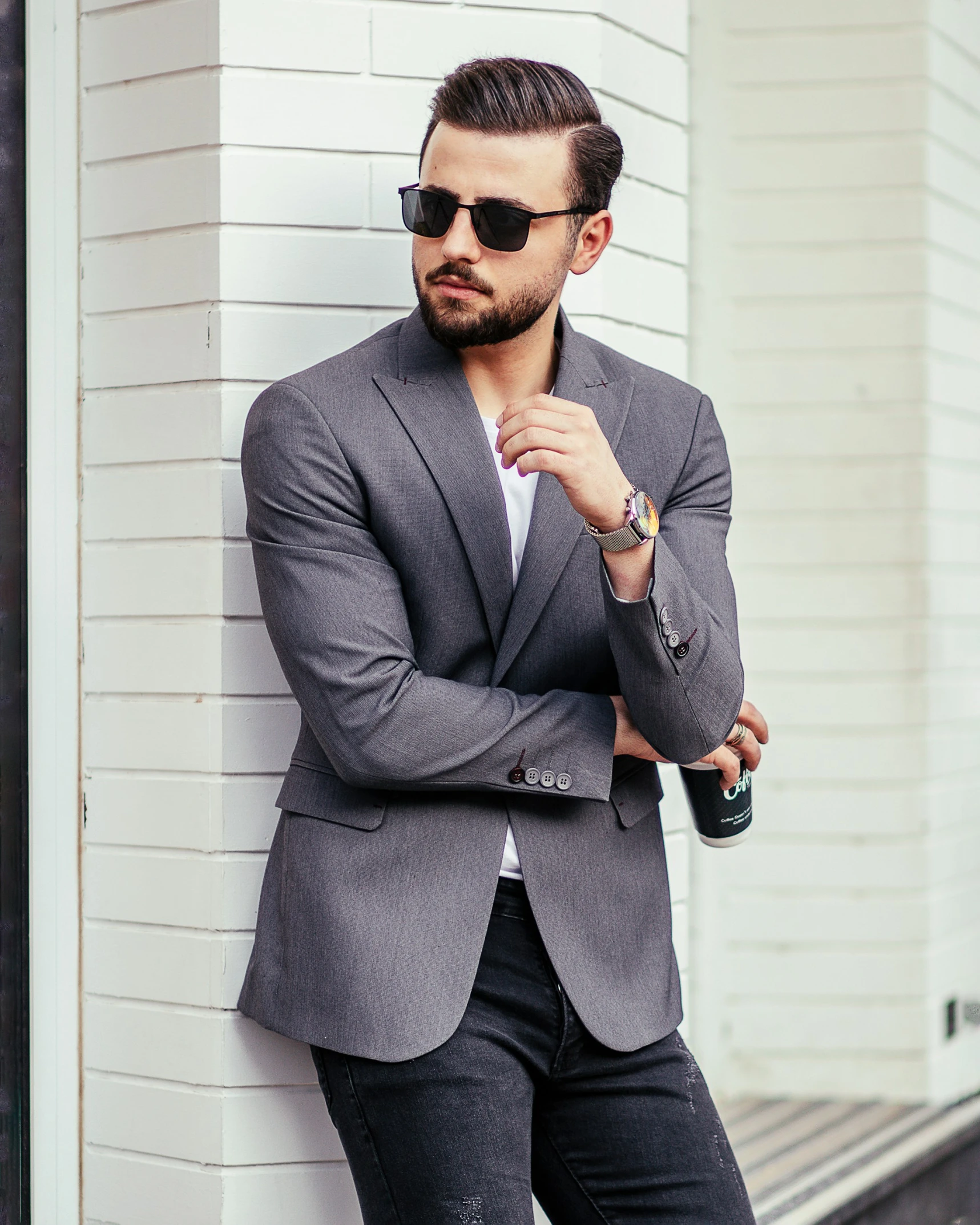 a man in grey blazer standing by a building