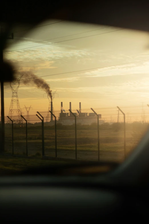 the view of power plant's smoke stacks through the fence