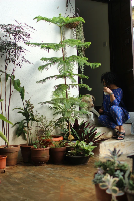 a woman reading a book while sitting in front of plants