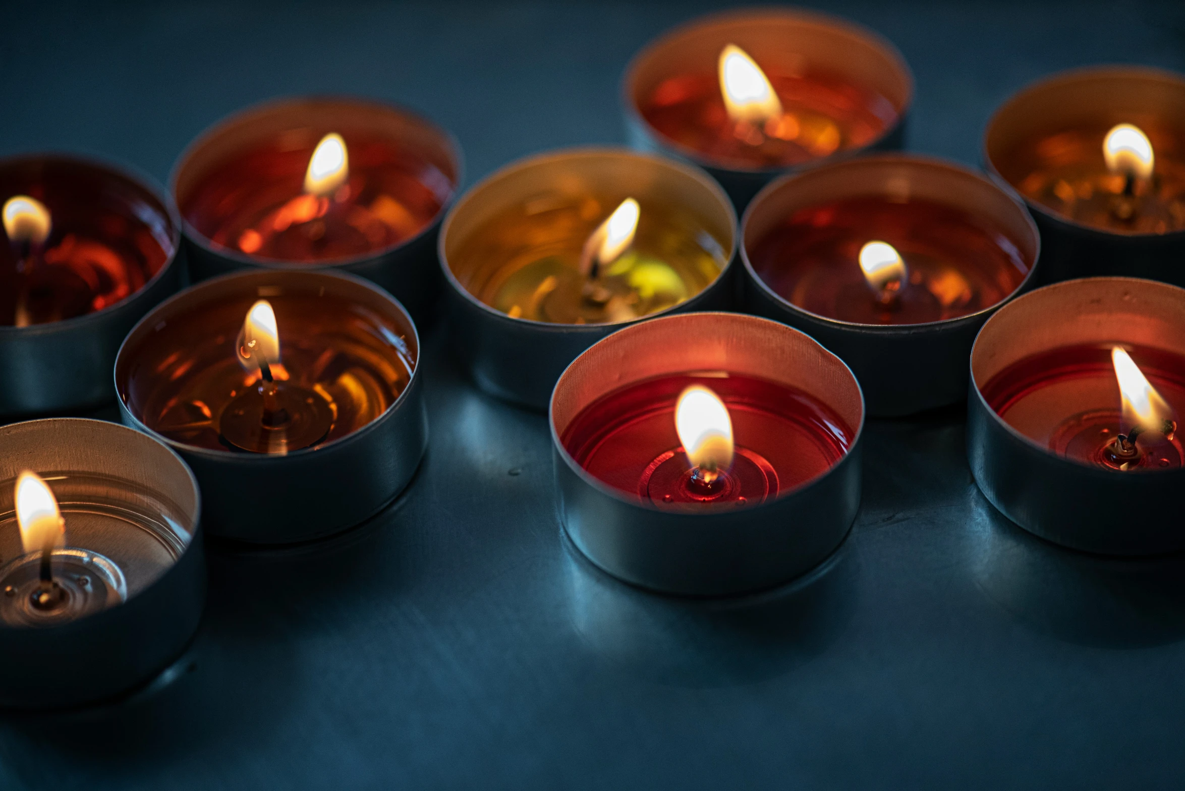 many different candles are lit in several bowls