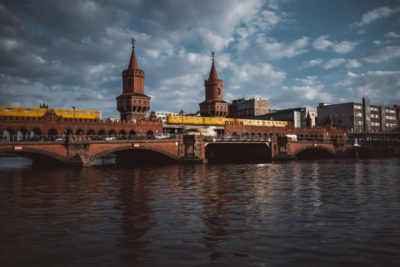 a bridge crossing the river with two towers in the background