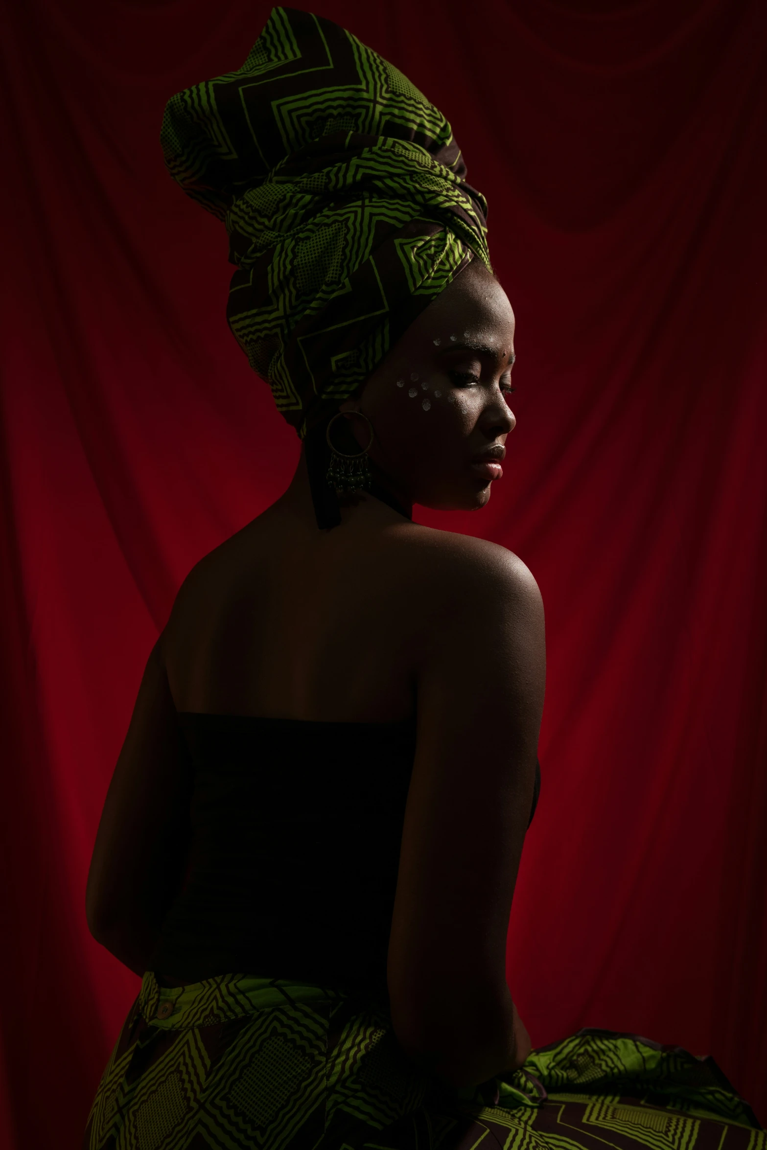 a lady in a green dress is against a red backdrop