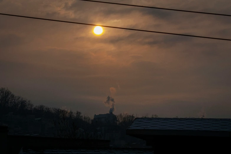 the sun is setting with power lines above it