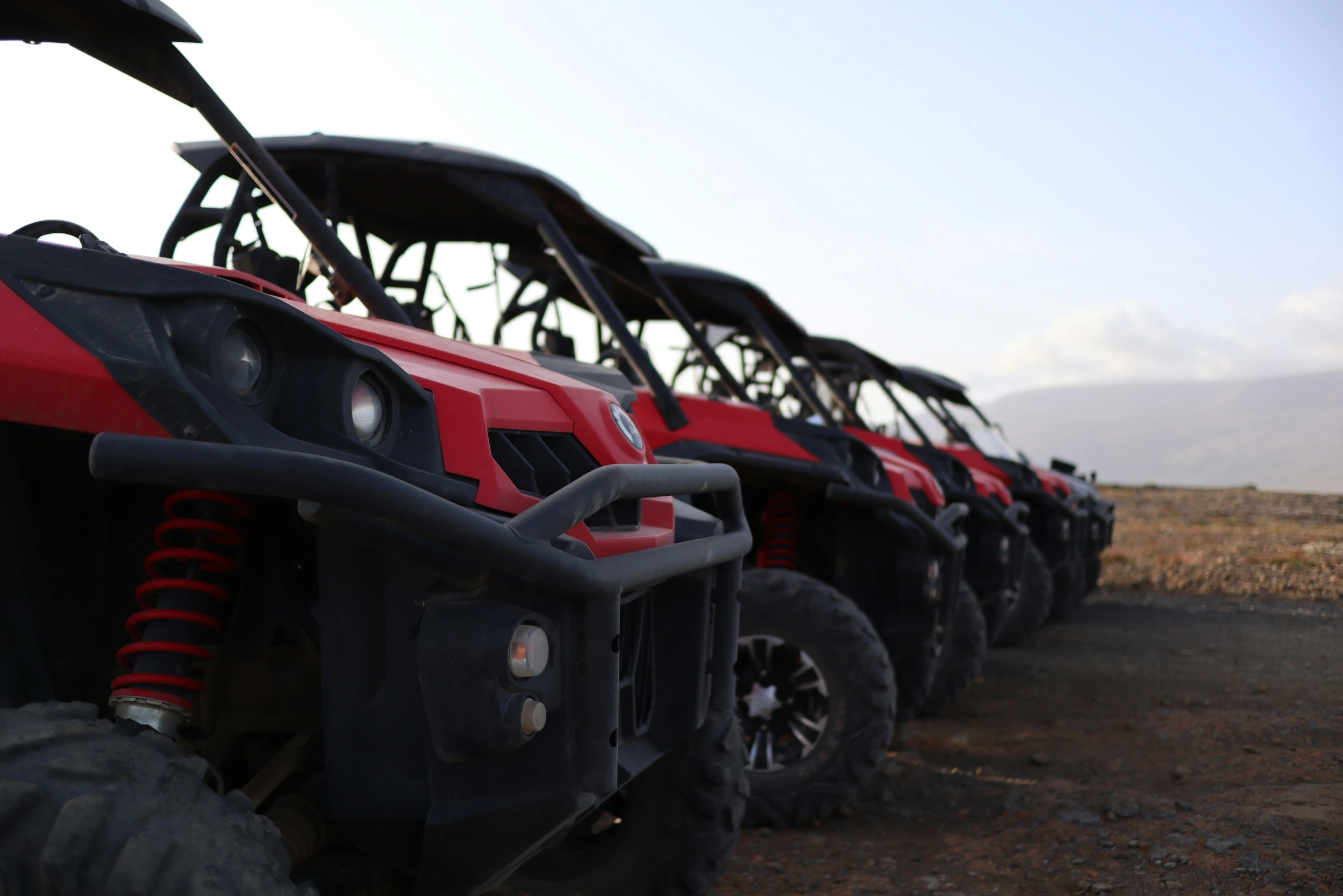 a line of red four wheelers with mud tires