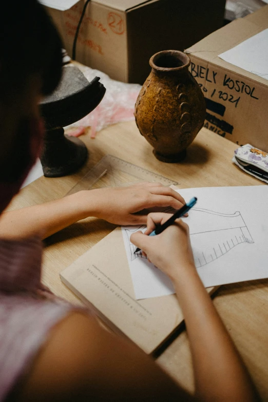 a woman writing on a piece of paper with a pen