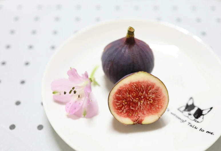 figs on a white plate next to flowers