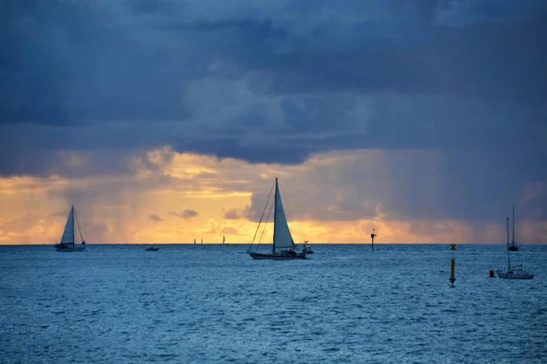 two sailboats in the ocean with stormy skies