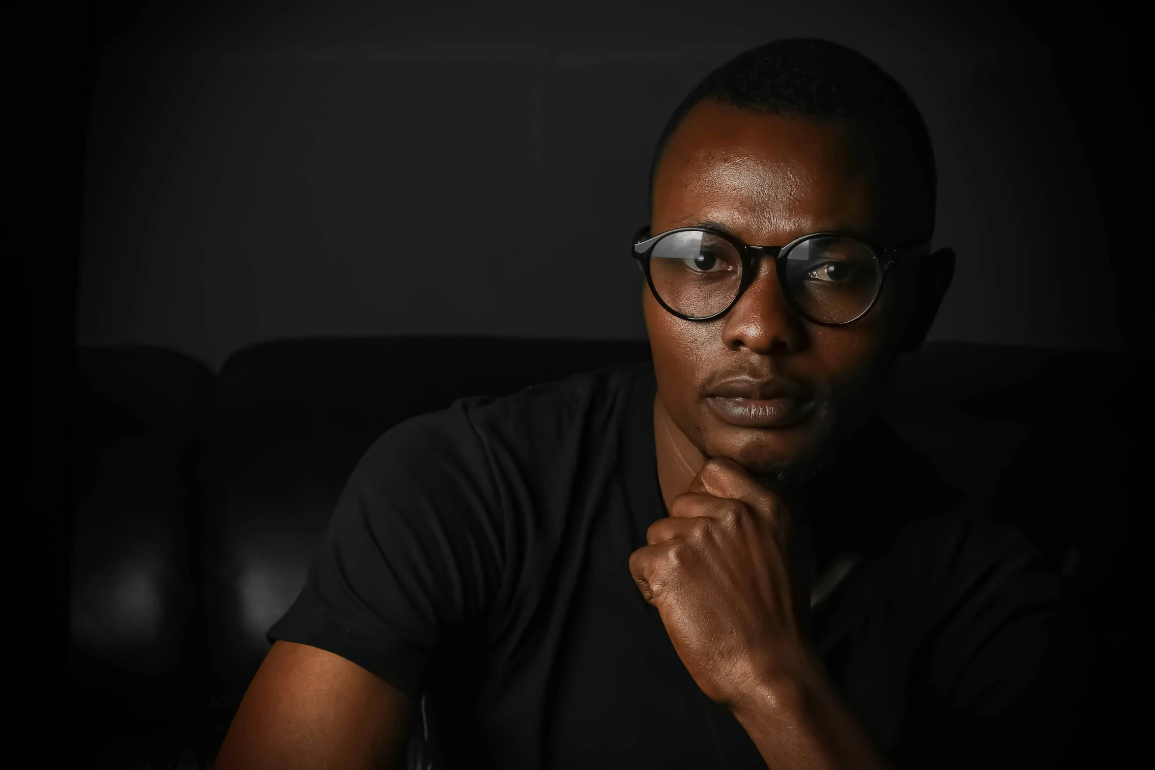 a man in black shirt and glasses sitting on chair