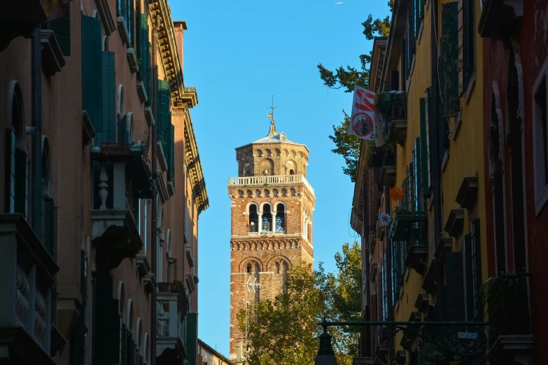 the view from the side of some buildings looking up at a tower