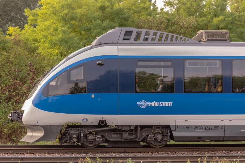 the blue and white passenger train is riding down the tracks