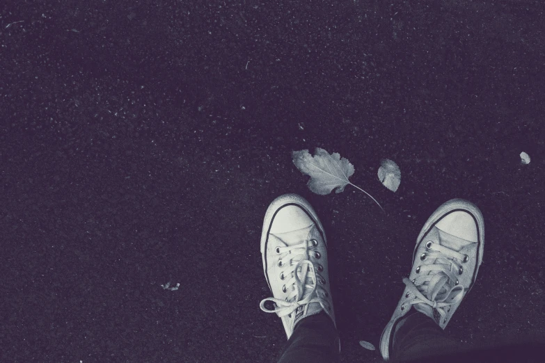 a pair of white sneakers on the ground in the night