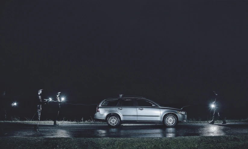 a white car is parked in front of street lights at night