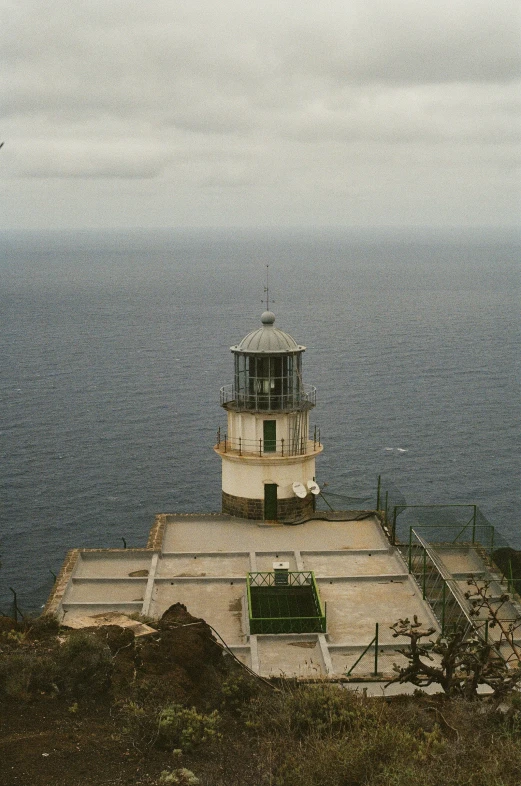 a white lighthouse sitting on top of a rock cliff next to the ocean