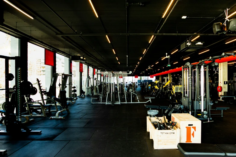 a gym with some gym machines and large windows