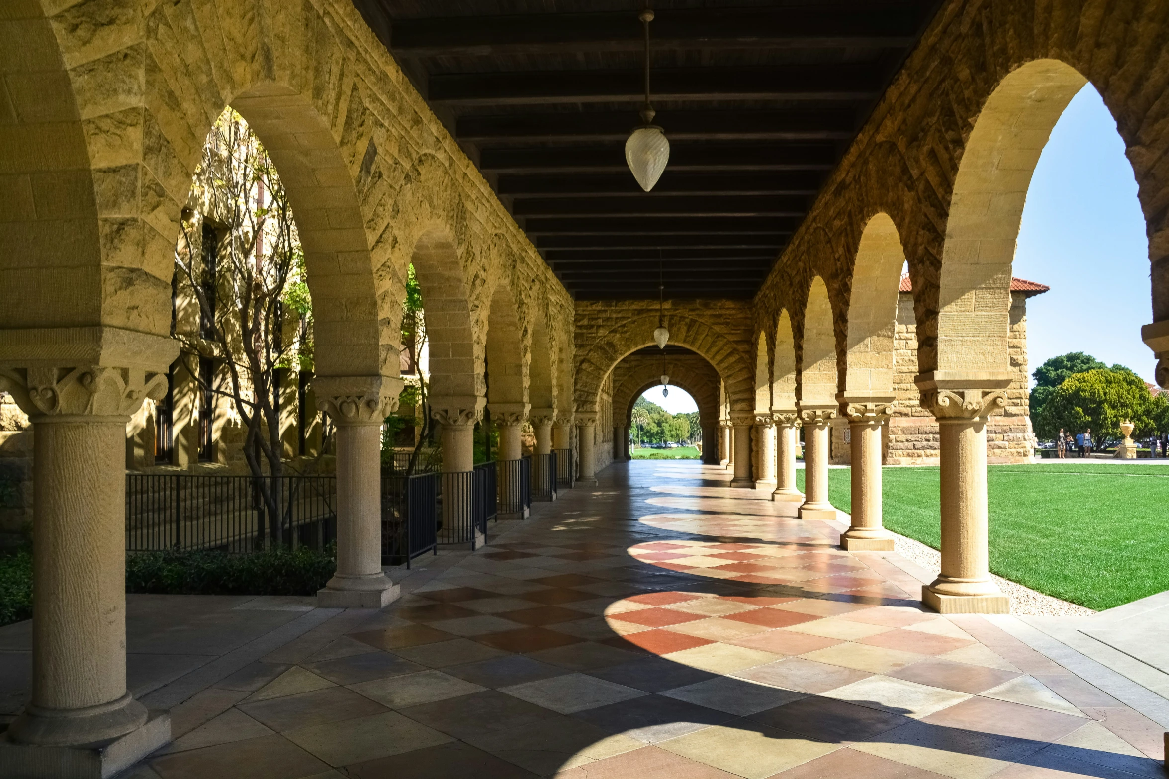 a courtyard with many pillars and walkway in the background