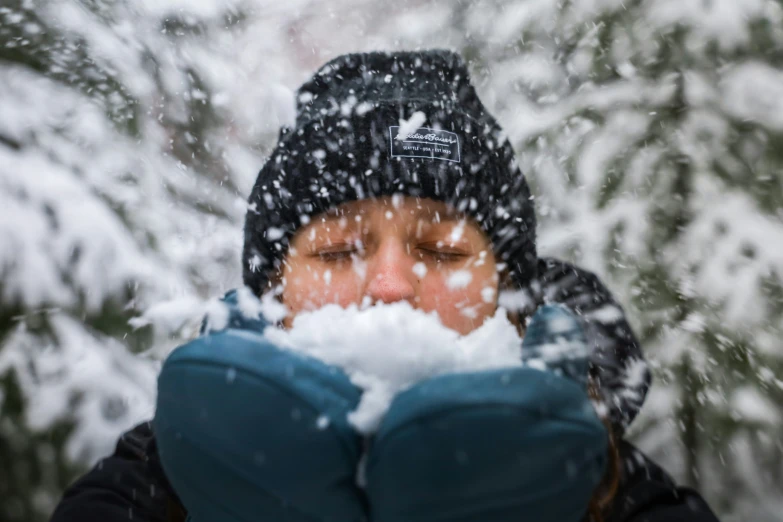 a woman is covering her face with a snowy cap