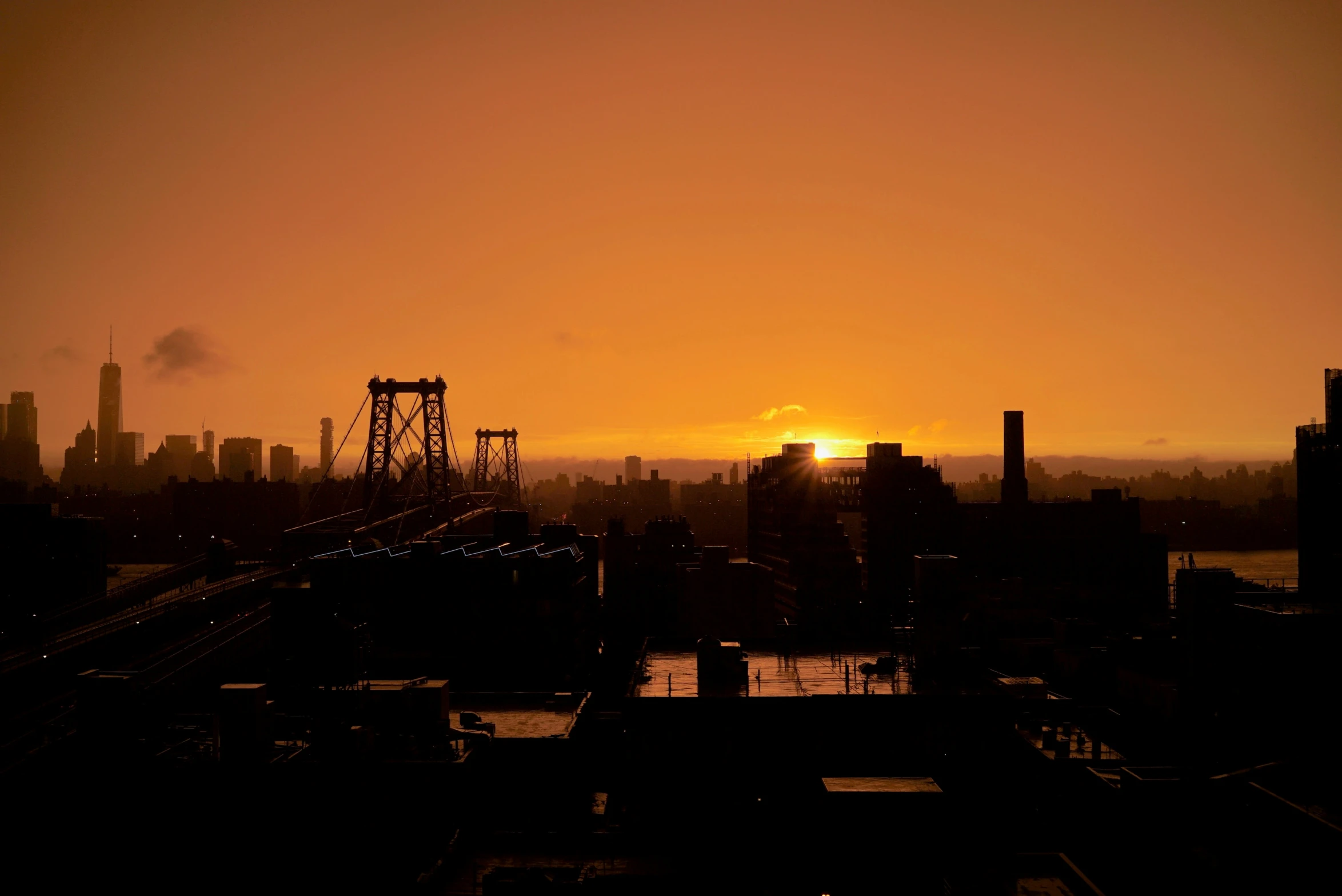 the sun sets over a city in a dark haze