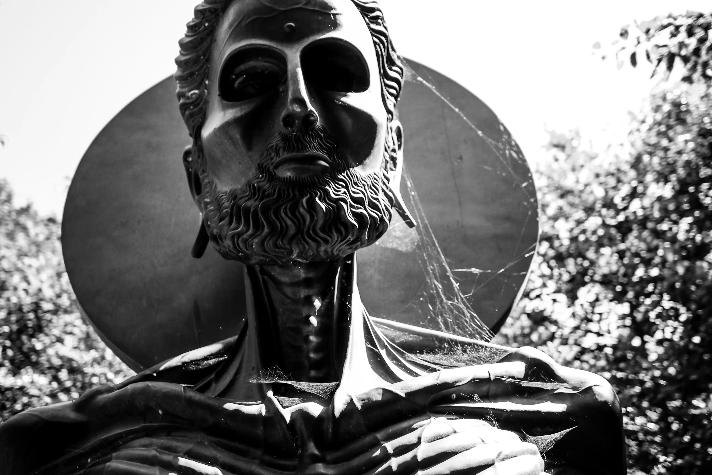 a sculpture with a man's face and beard holding a circular object