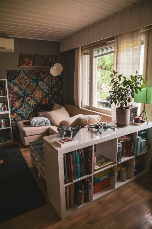 a small book shelf with a couch in front of a window