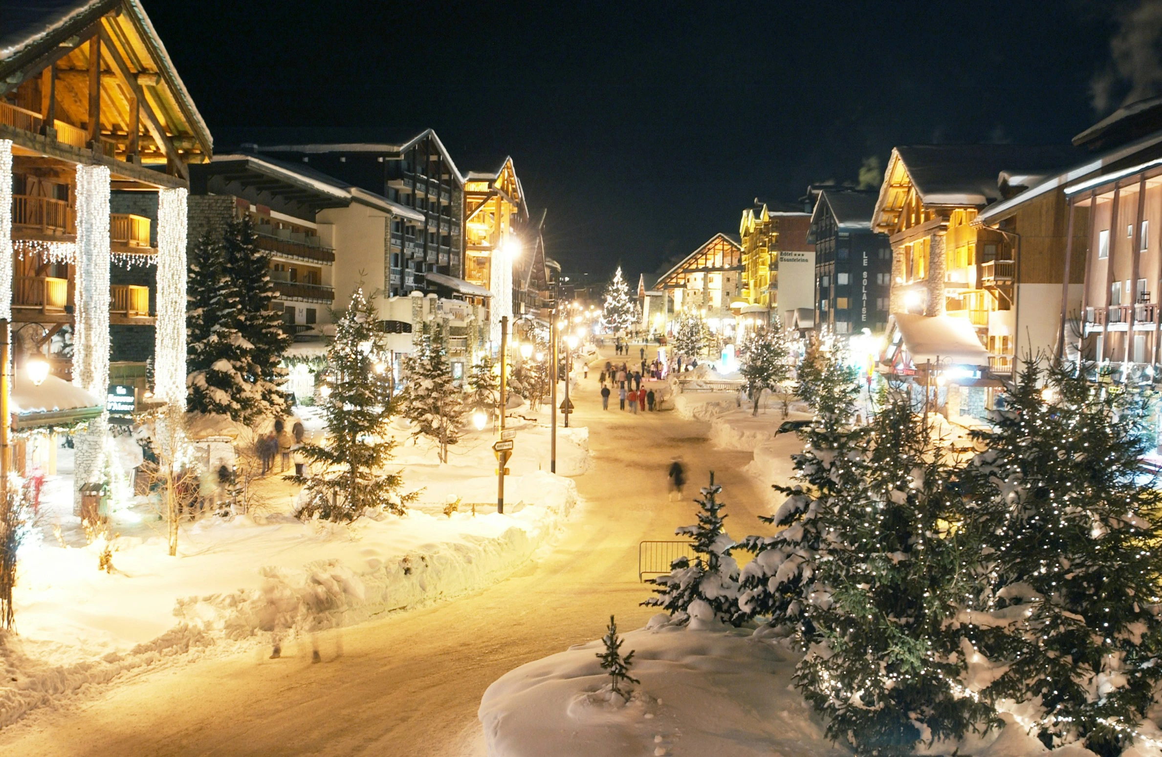 a town with buildings lit up and decorated in christmas lights