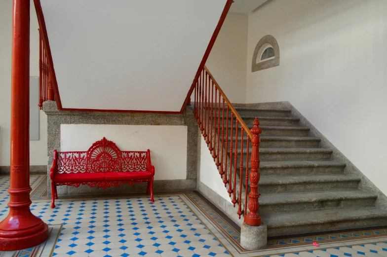 the red bench is on the tiled floor