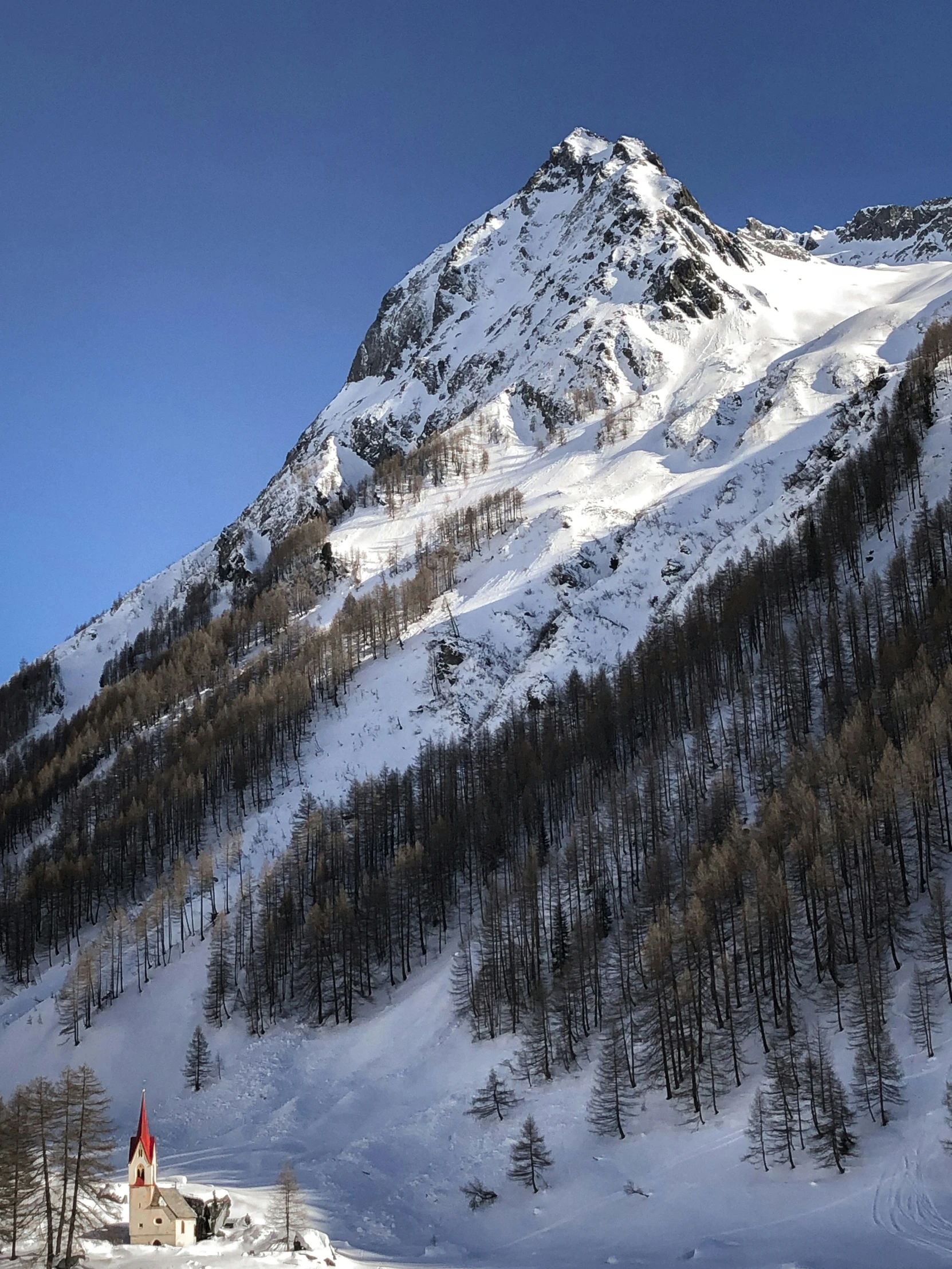 the mountains covered in snow, trees and clouds