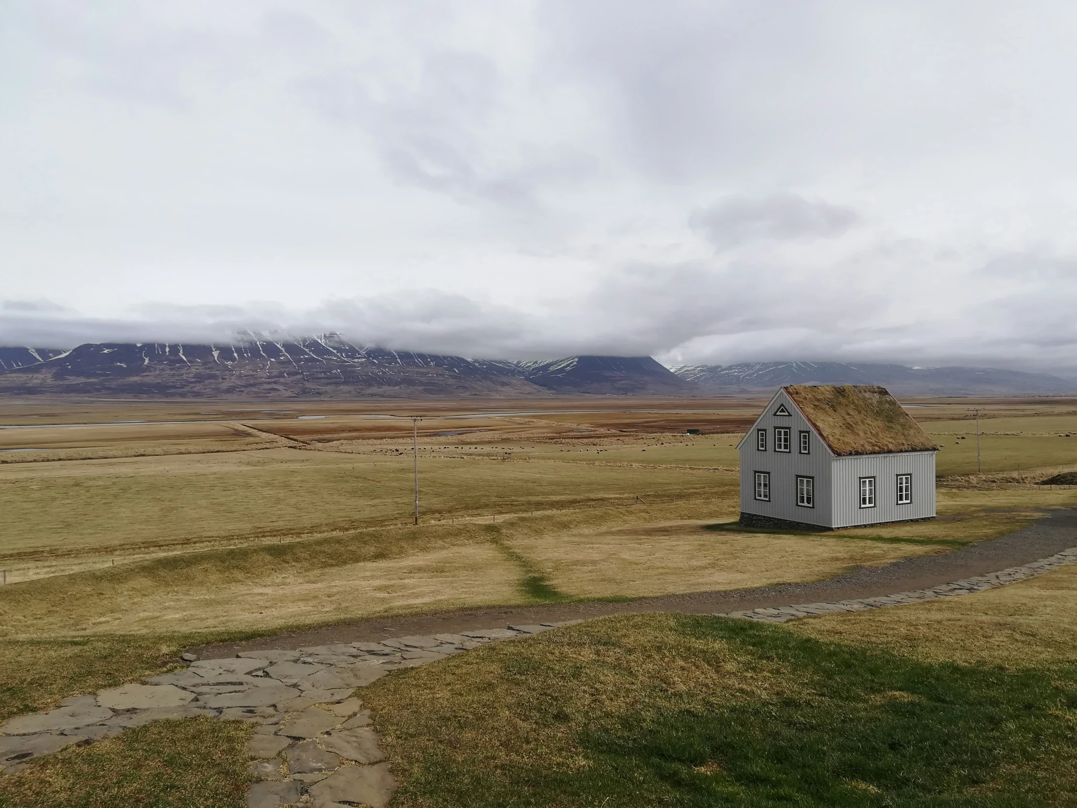 a house in an empty field with some mountains in the background