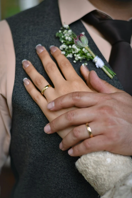 the couple are holding hands, one is wearing wedding rings