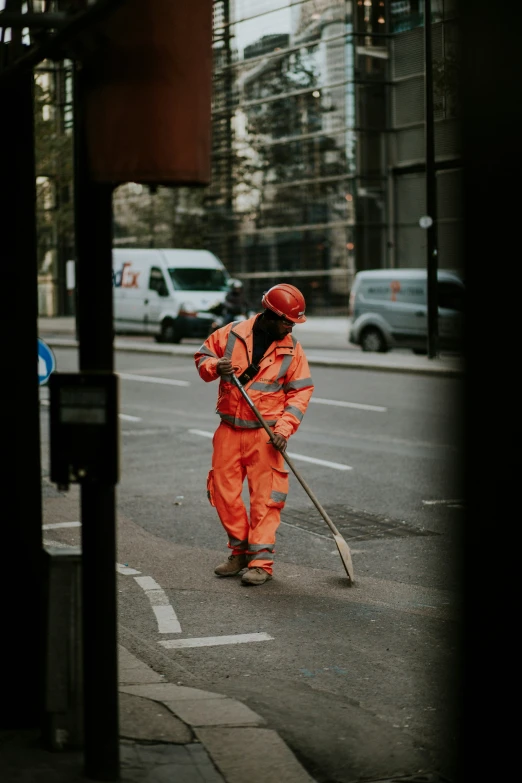 a man wearing an orange jumpsuit with a walking stick and wearing a red helmet