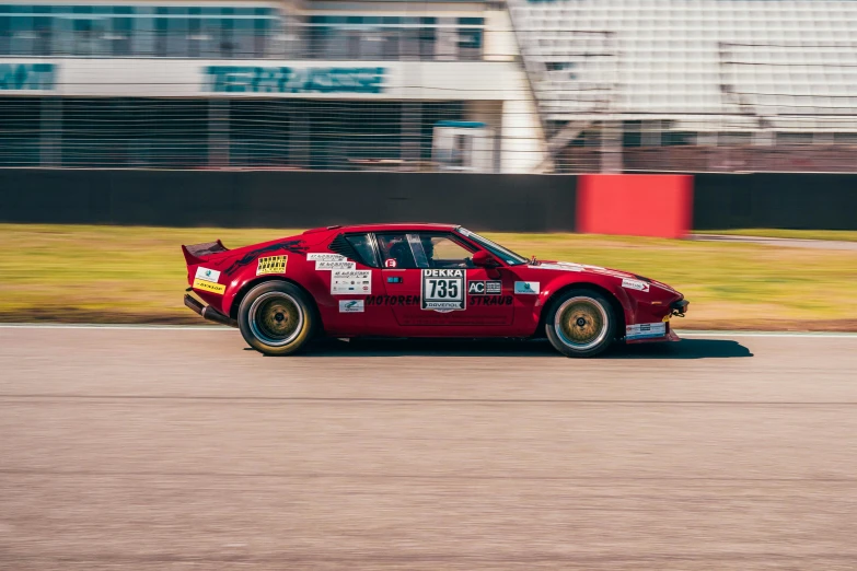 a red car with gold rims drives down the track