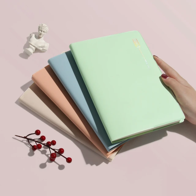 three notebooks with a pencil inside, three colors are on a light background